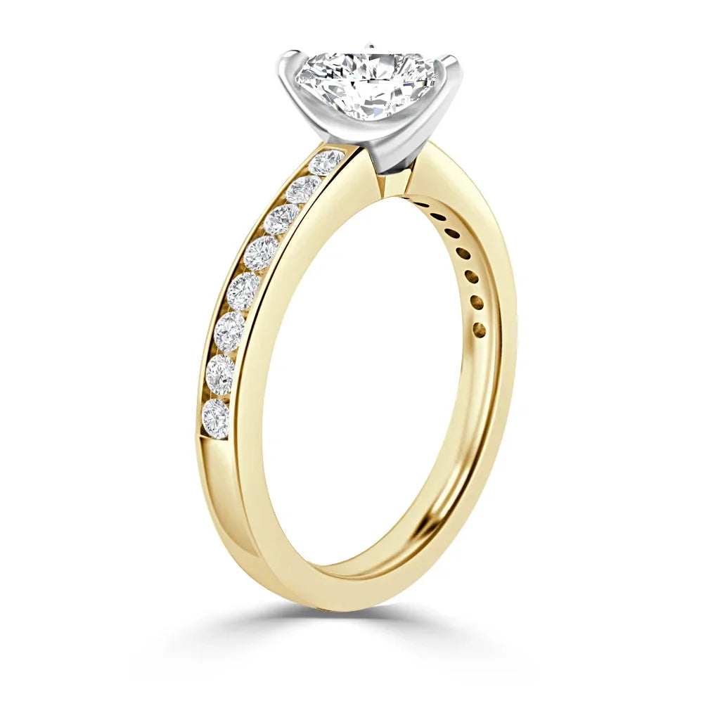 Gold ring with side diamonds and a large round center diamond in a white gold prong setting, shown upright.