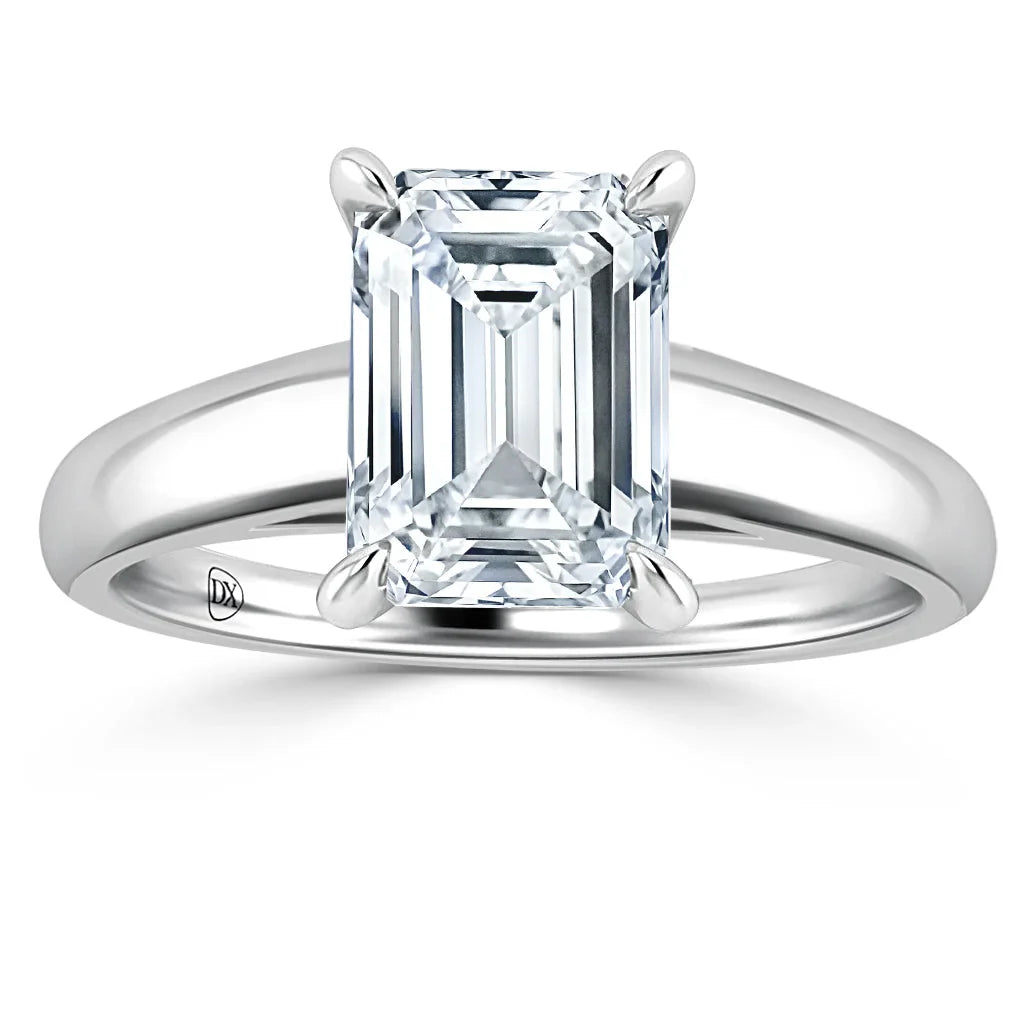 Emerald-cut diamond solitaire ring with a plain, polished white metal band on a white background.