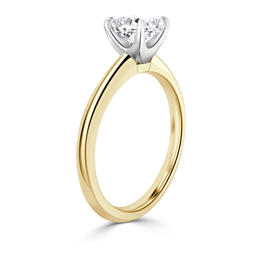 Yellow gold ring with a round diamond in a white gold four-prong solitaire setting, shown from the side.