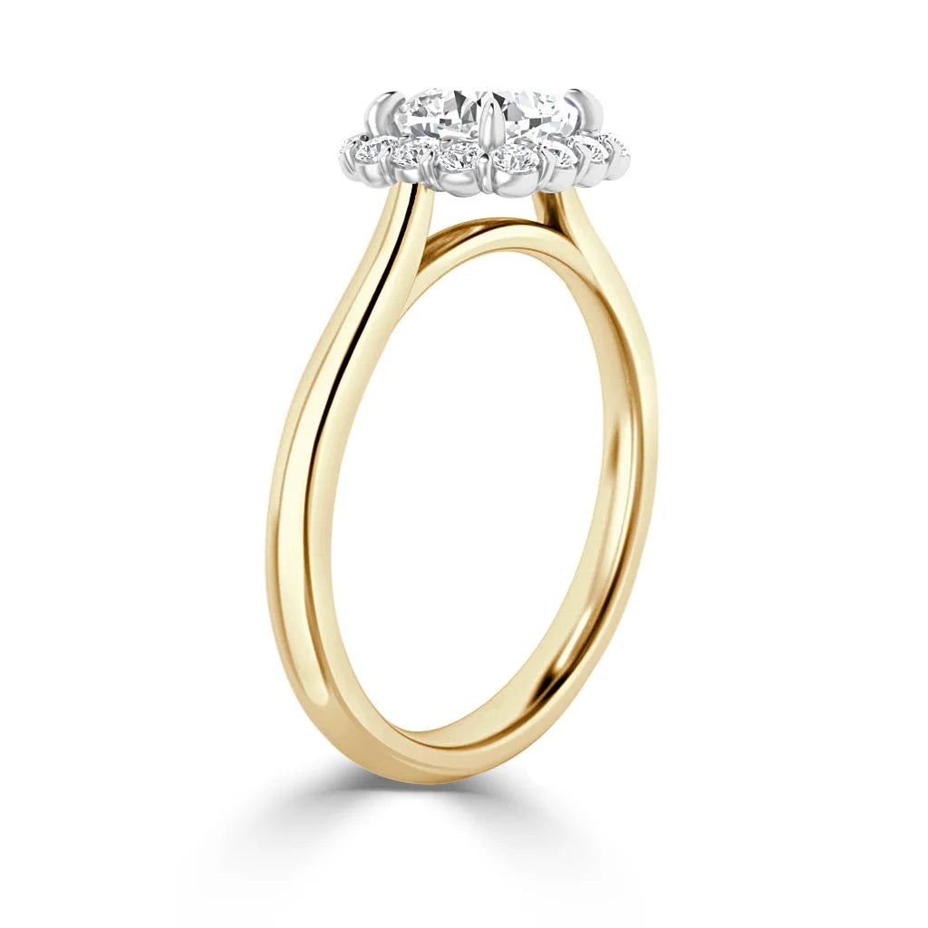Gold ring with a round diamond cluster halo setting, viewed from the side against a white background.