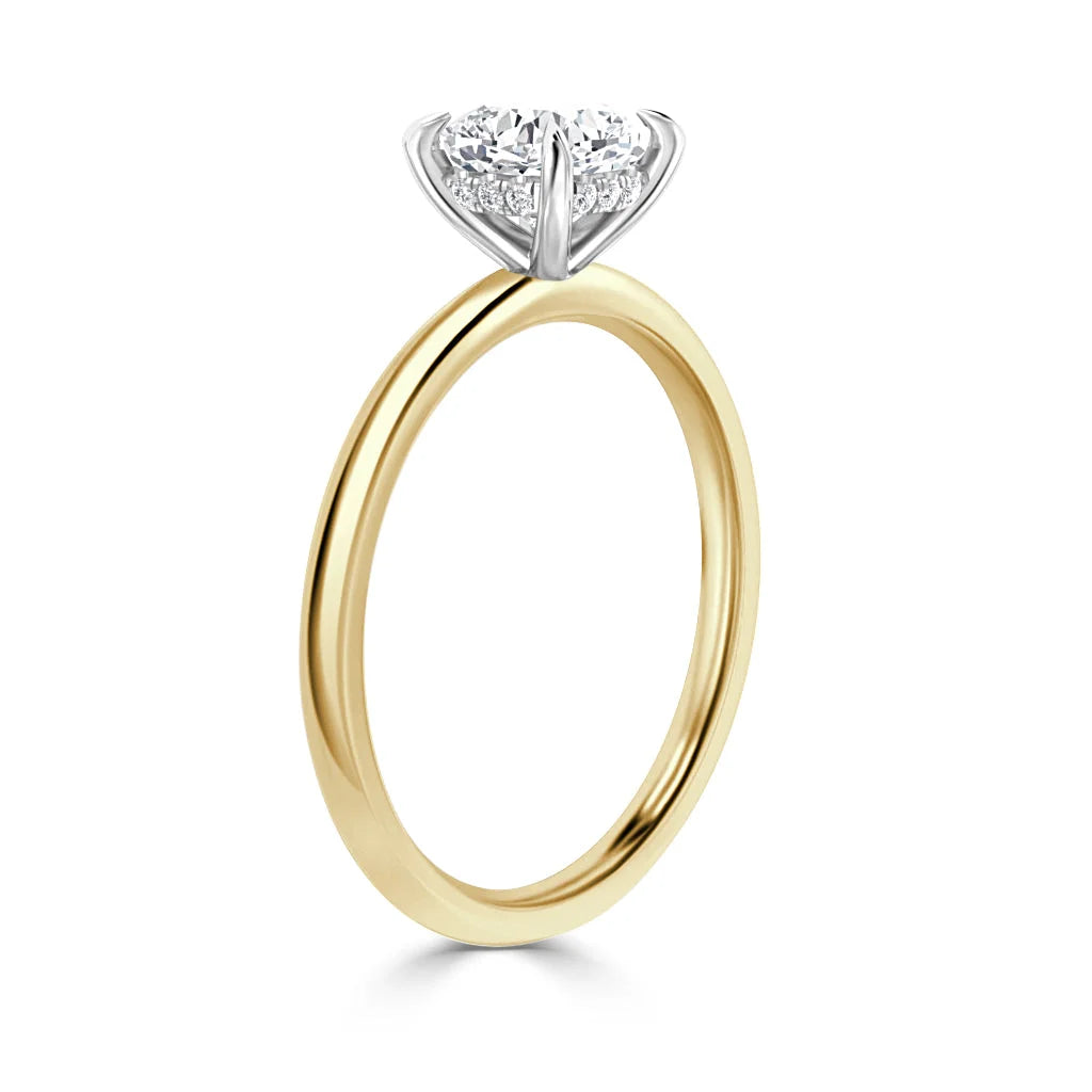 Gold band solitaire ring with a round, prong-set diamond in a white gold setting, viewed from the side.