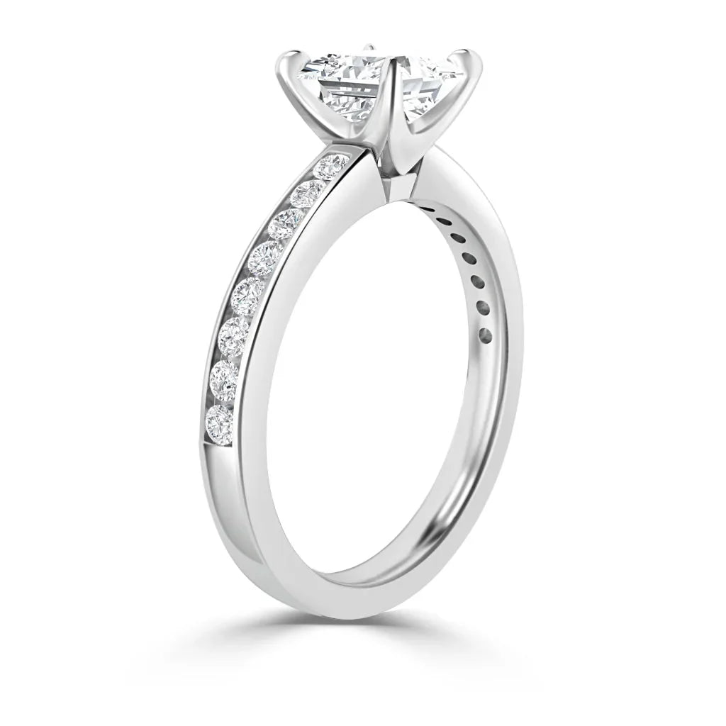 A white gold ring with a round solitaire diamond and smaller diamonds set along the band.