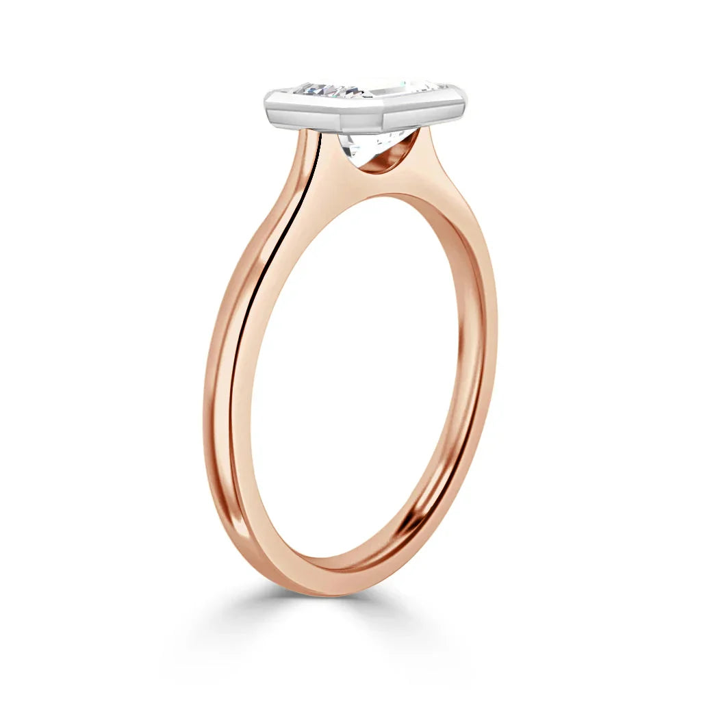 Rose gold ring with a thin band and a horizontally set oval diamond in a white gold bezel setting.
