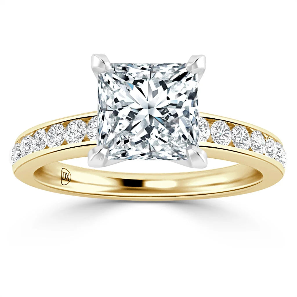 A gold ring with a large princess-cut diamond and smaller diamonds set along the band, on a white background.