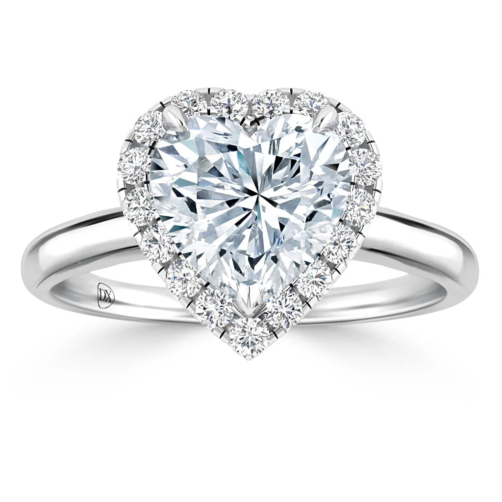Heart-shaped diamond ring with a halo of smaller diamonds on a silver band, shown on a white background.