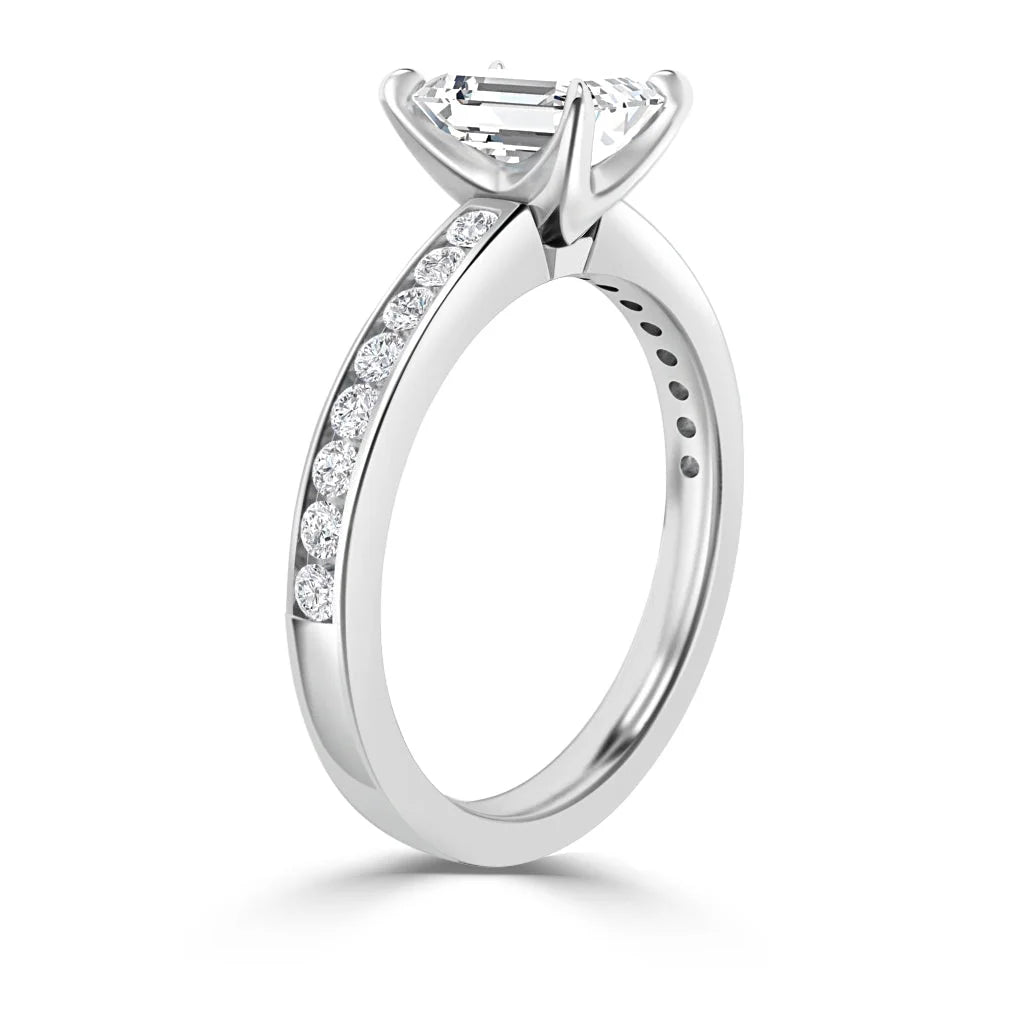 A white gold ring with a large emerald-cut diamond and smaller diamonds set along the band.
