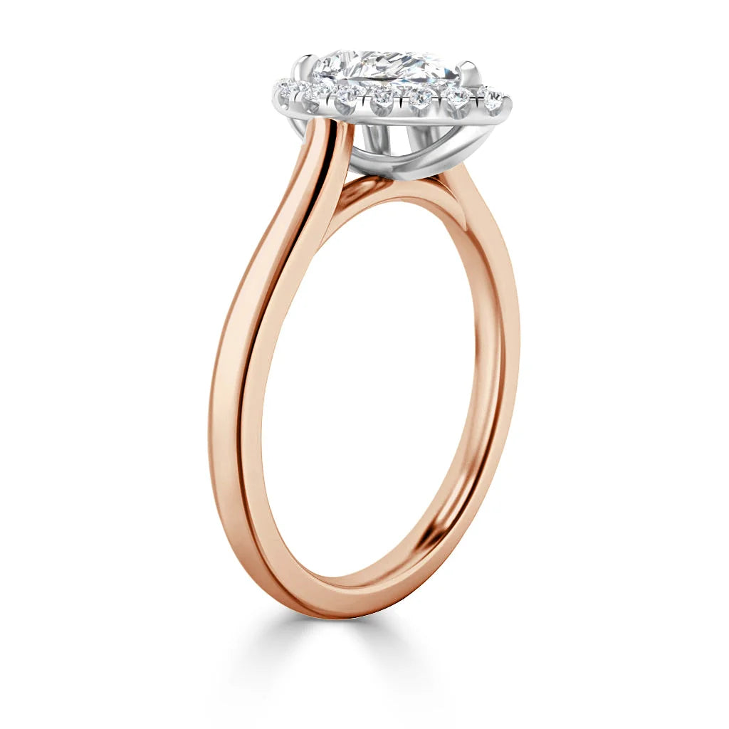 Rose gold ring with a round diamond halo setting, shown from a side angle against a white background.
