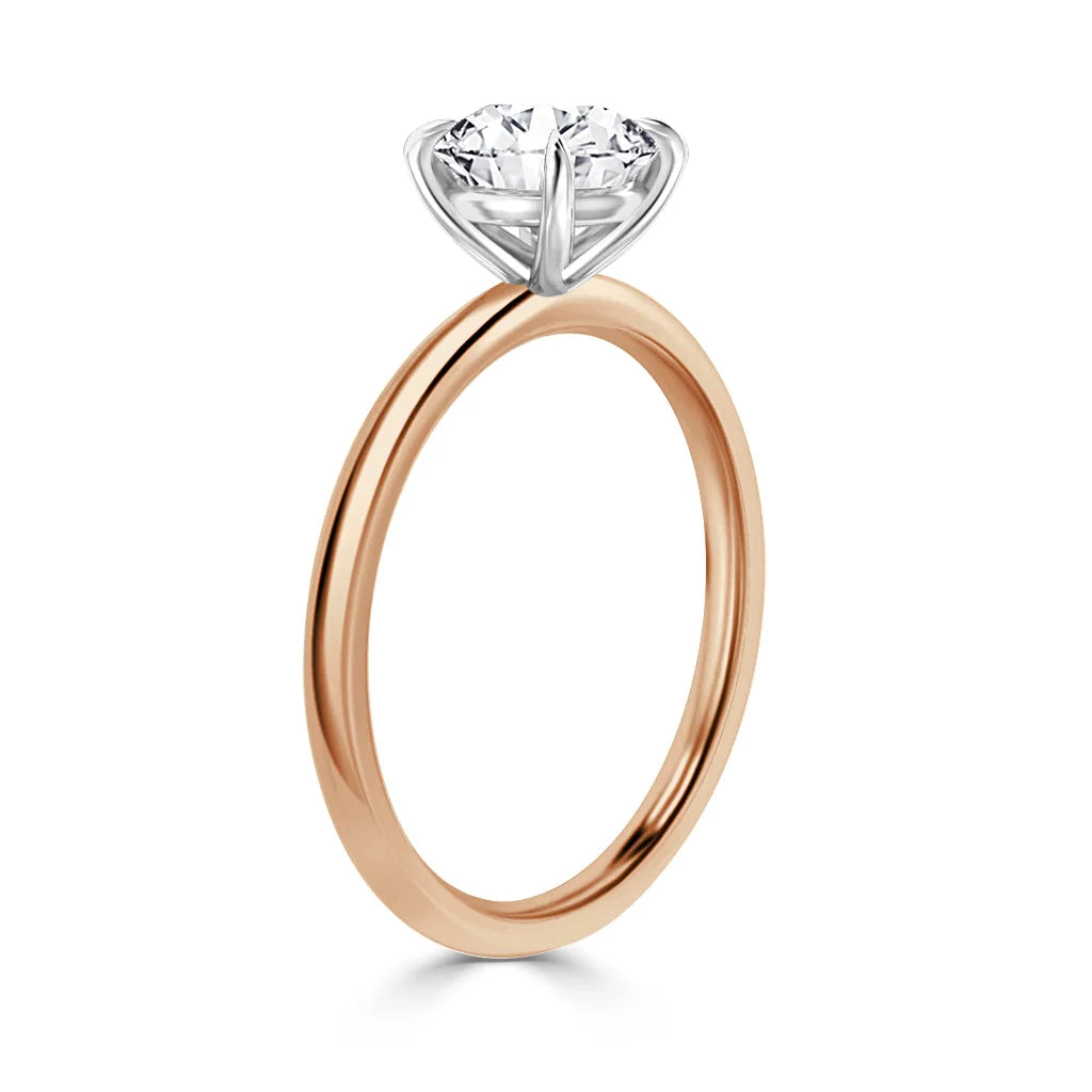 A rose gold band solitaire ring with a round, prong-set diamond viewed from the side on a white background.