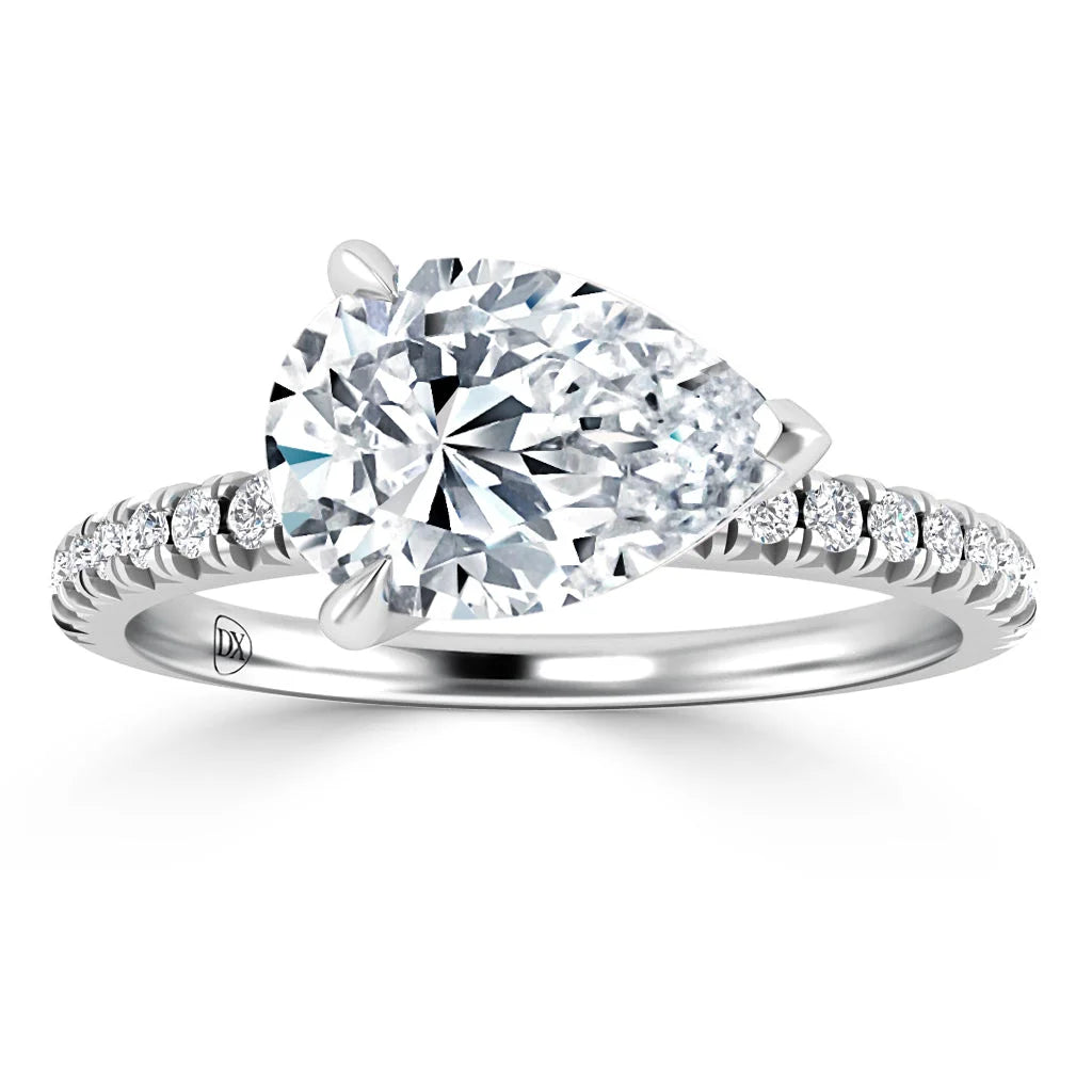 A pear-shaped diamond ring with a pavé diamond band, set in white metal, shown on a white background.