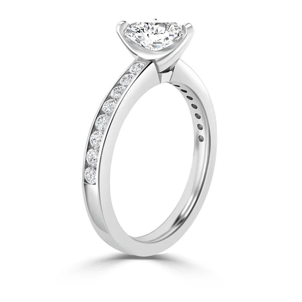 Silver engagement ring with a round center diamond and smaller diamonds set along the band, side view.