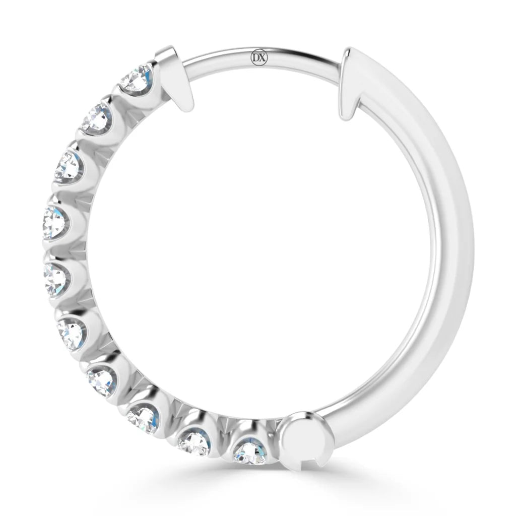 A silver hoop earring with embedded clear gemstones along half of its outer edge, shown on a white background.