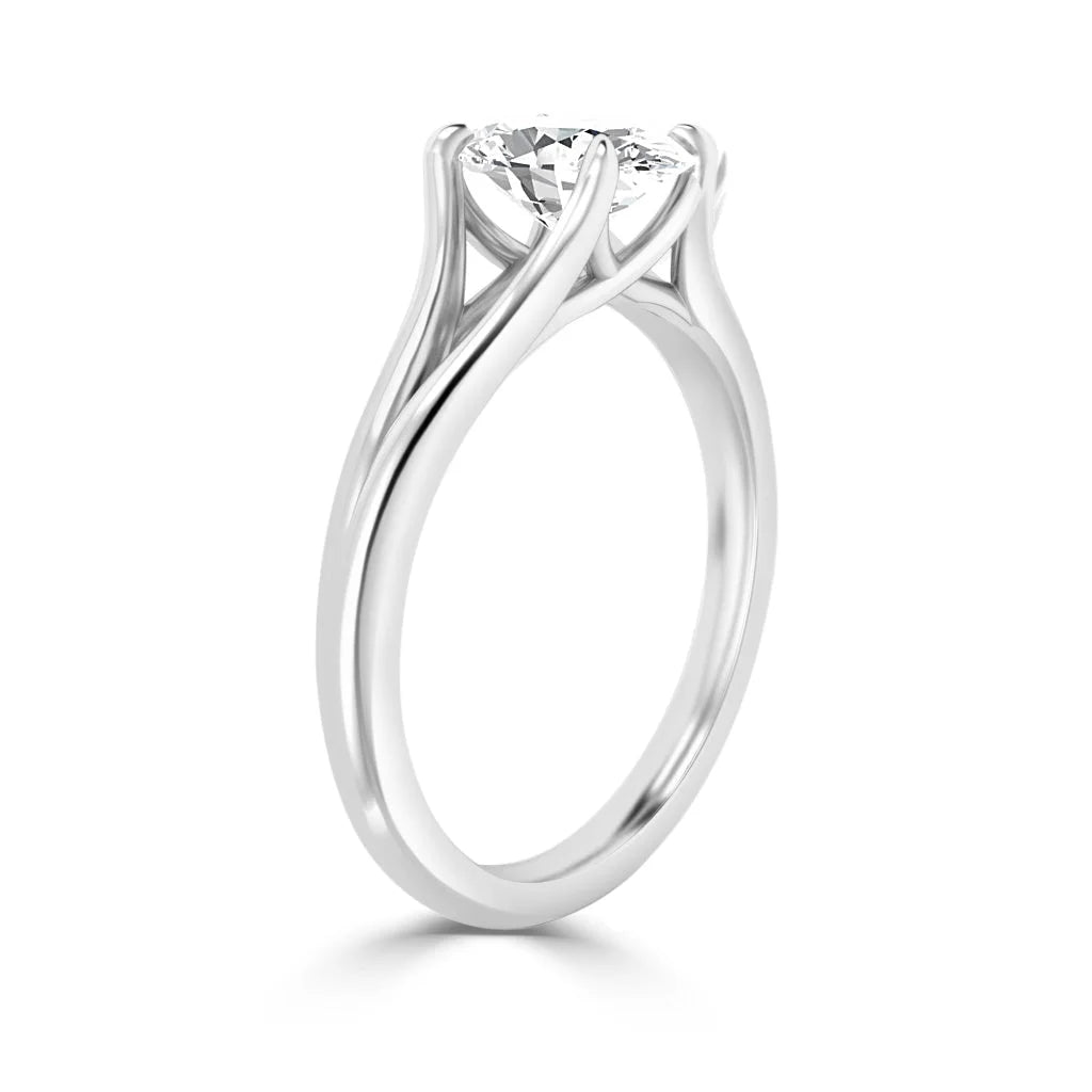 A silver ring with a round diamond held by four elegant, twisting prongs against a white background.
