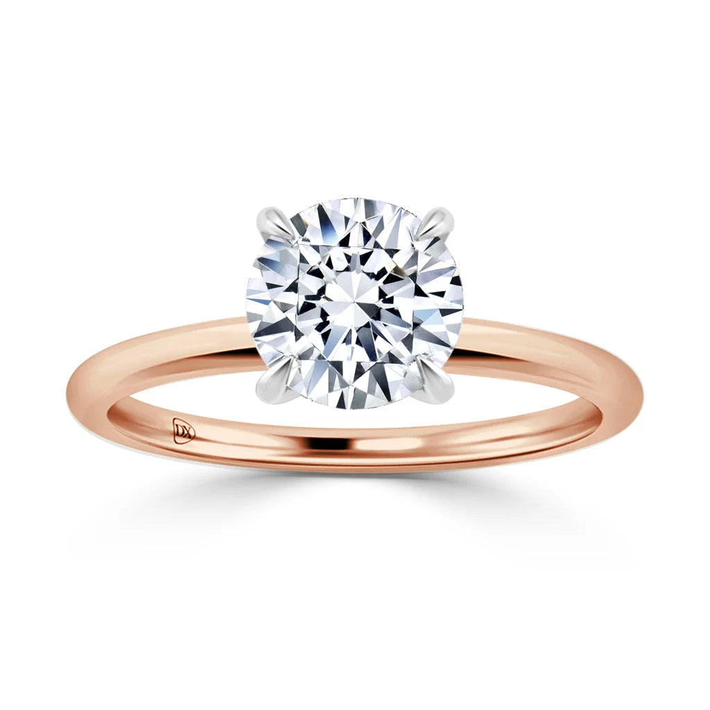 A solitaire diamond ring with a round-cut stone on a simple rose gold band and four prongs.