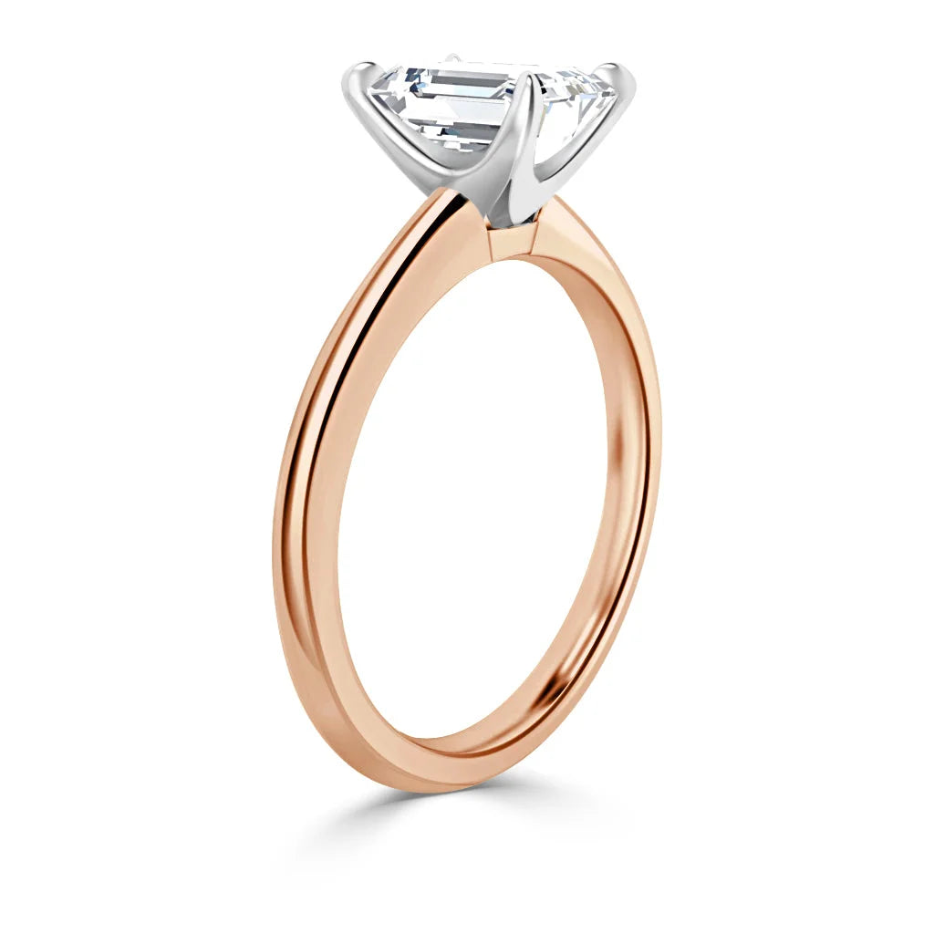 Rose gold ring with a large rectangular diamond in a white gold prong setting, viewed from the side.