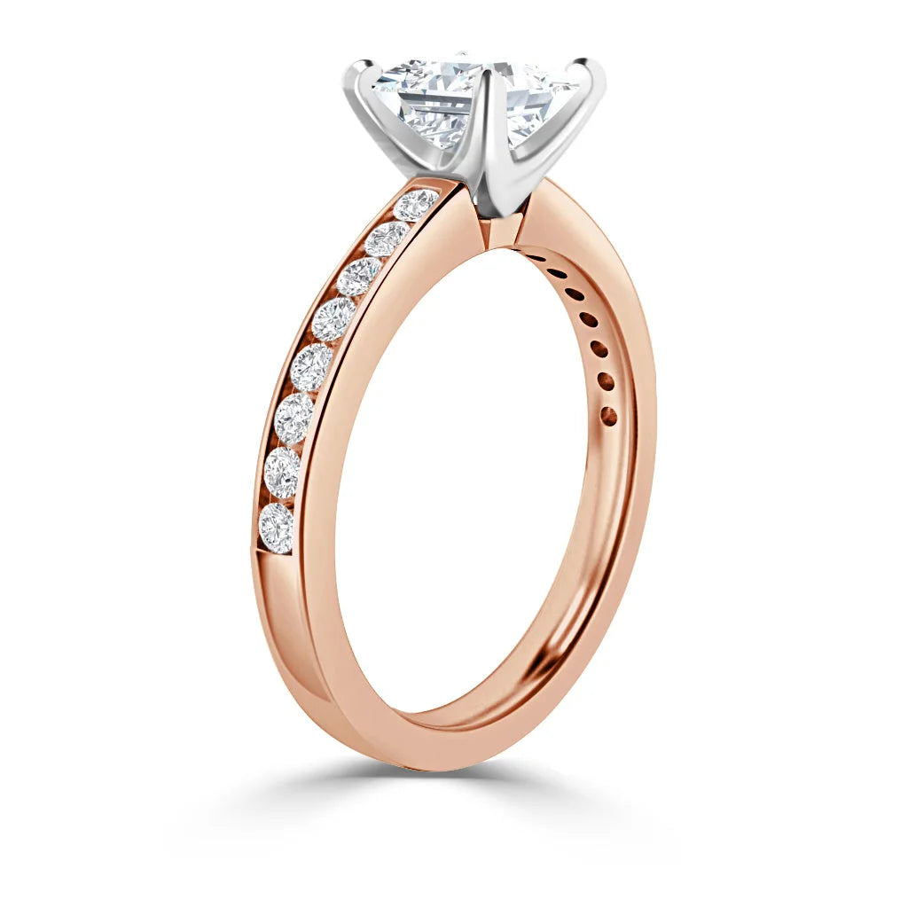 Rose gold ring with side diamonds and a large round solitaire in a white gold prong setting, on white background.