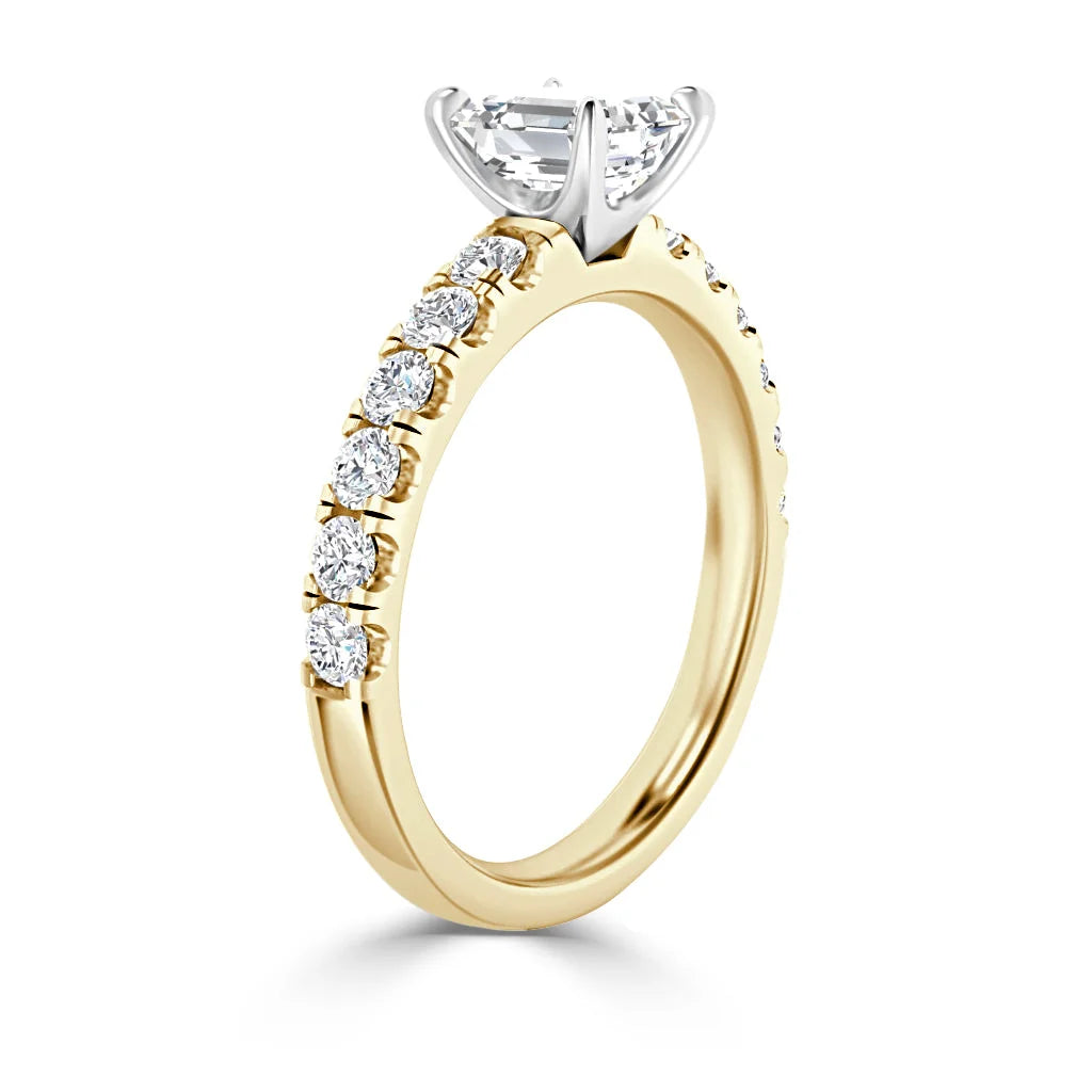 A gold ring with round diamonds along the band and a large solitaire diamond in a prong setting on top.