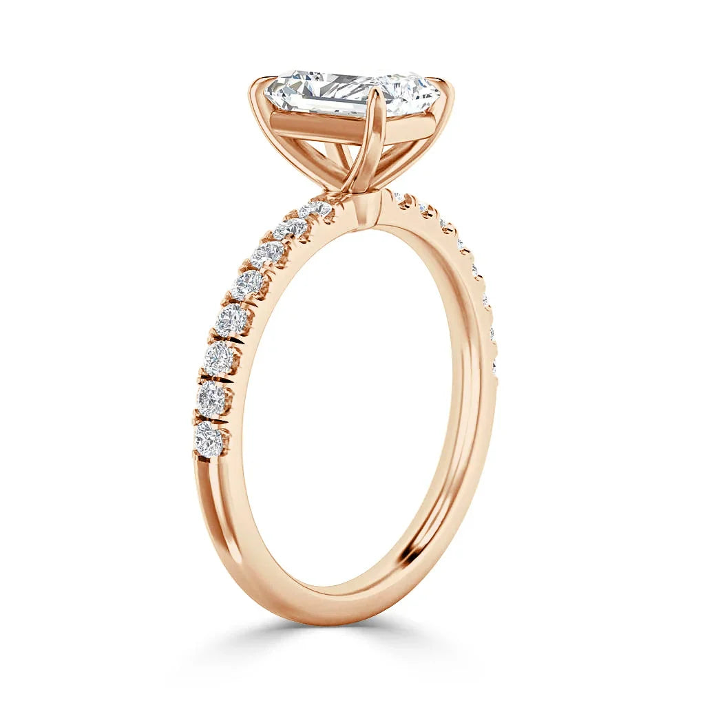 A rose gold ring with a large oval diamond center stone and small diamonds on half of the band.