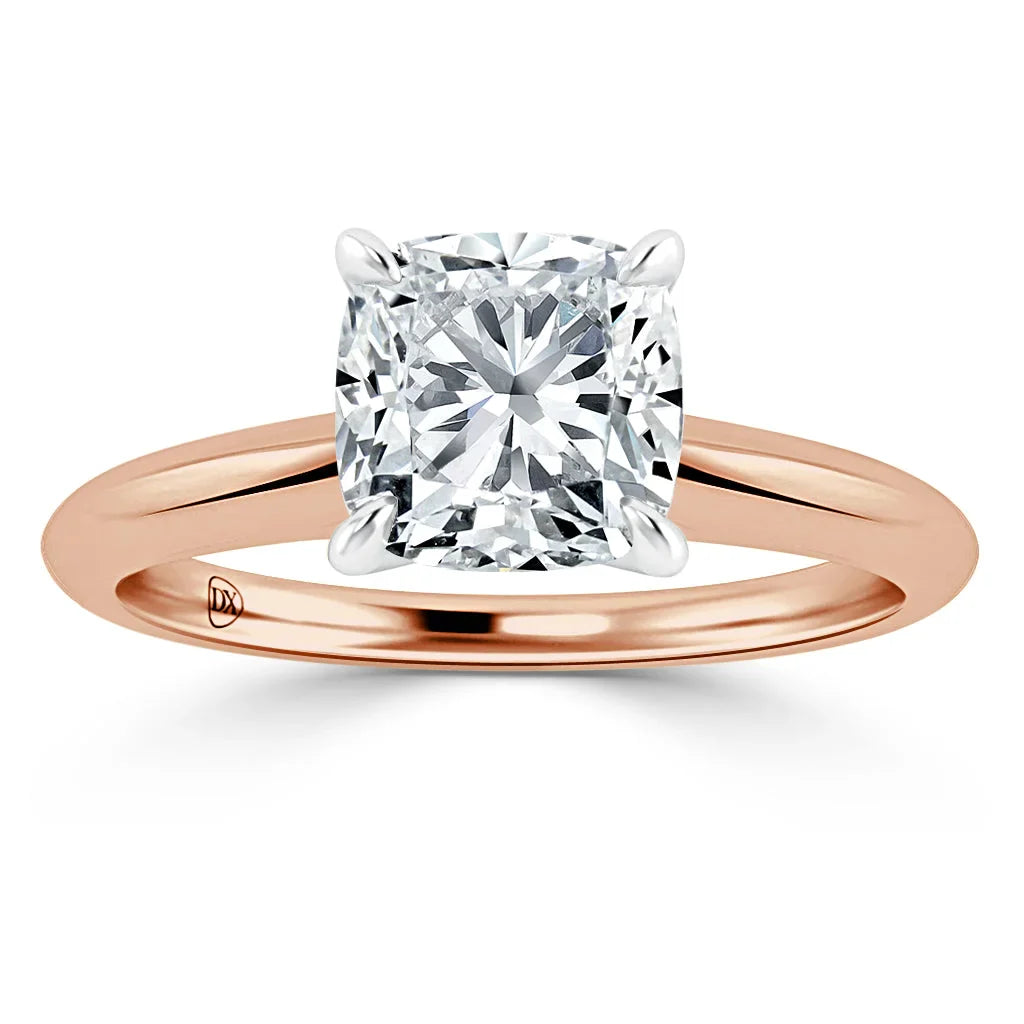 A cushion-cut diamond solitaire on a rose gold band with four prongs securing the gemstone.