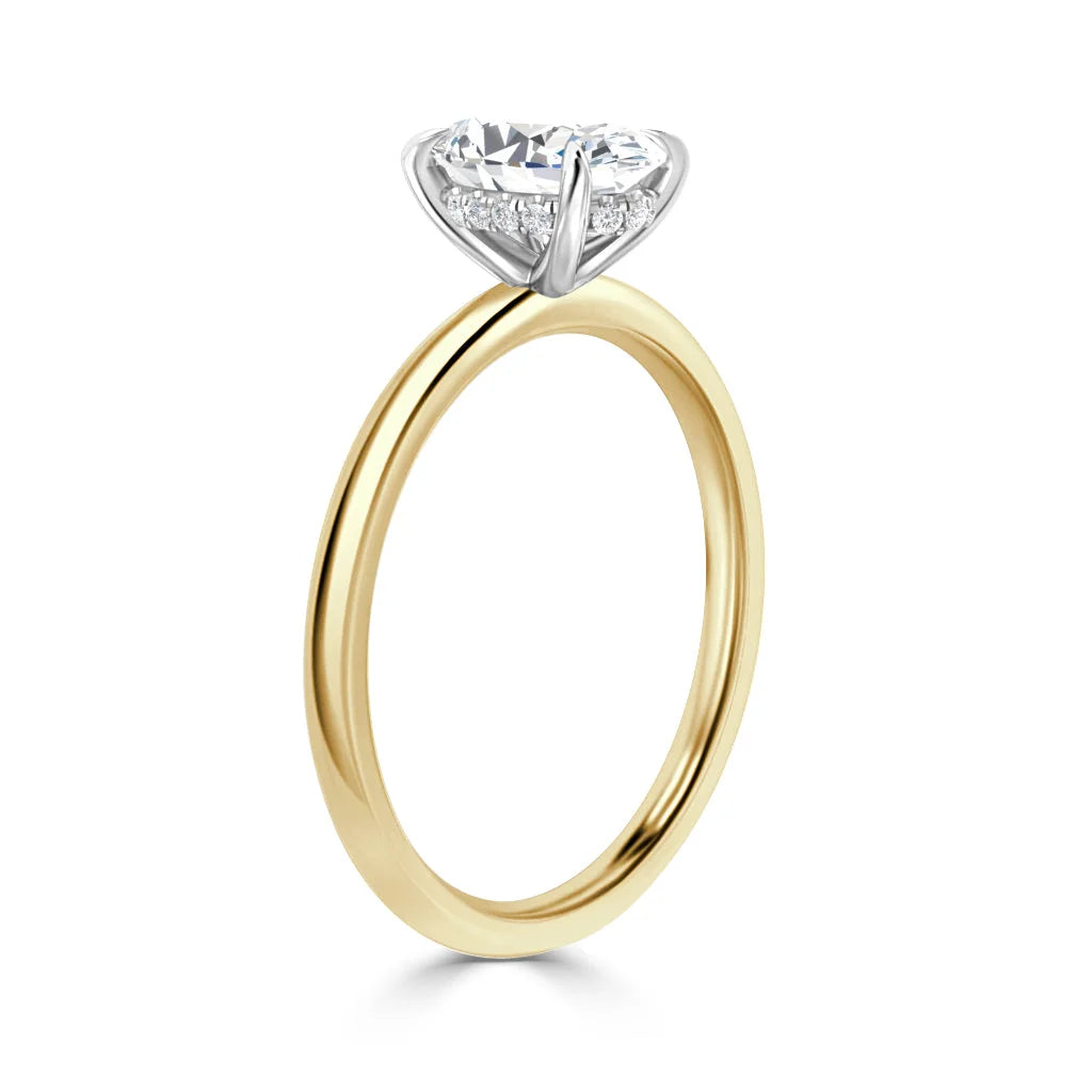A gold ring with a round diamond solitaire held by a white gold prong setting on a plain band.