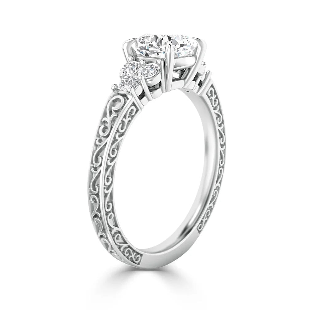 White gold ring with a large center diamond, two side stones, and intricate scrolling filigree on the band.