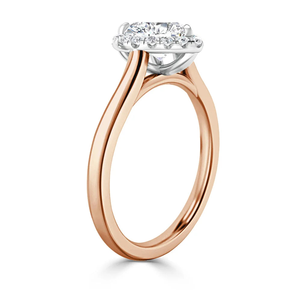 Rose gold ring with a round diamond halo setting and slim band, viewed from an angled side perspective.