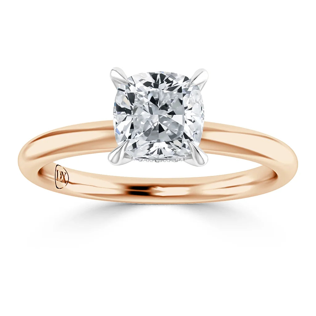A cushion-cut diamond solitaire ring with a rose gold band and white gold prongs, shown on a white background.