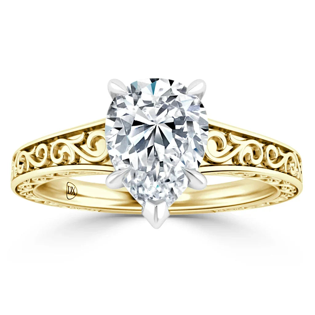 Oval diamond solitaire ring with ornate gold band featuring intricate swirling engravings.