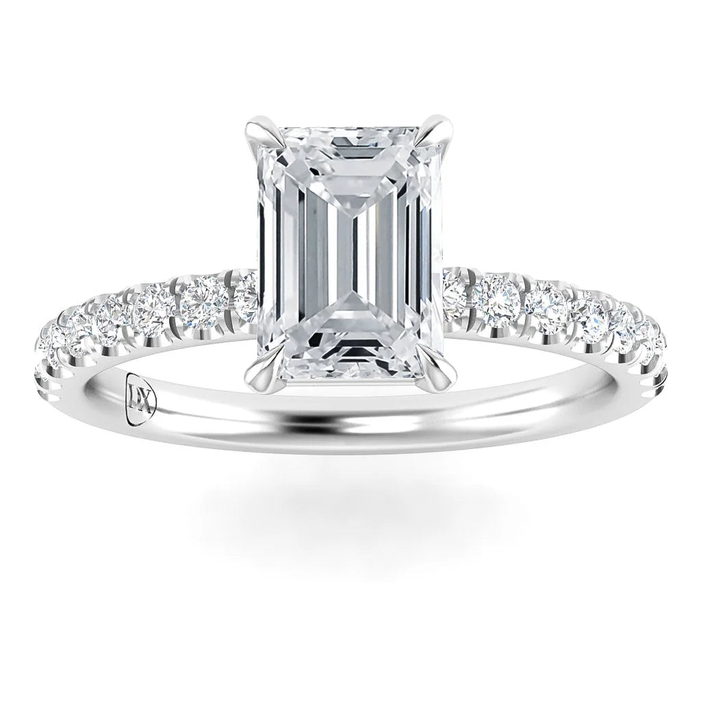 Emerald-cut diamond ring with a pavé diamond band, set in polished white metal, photographed on a white background.