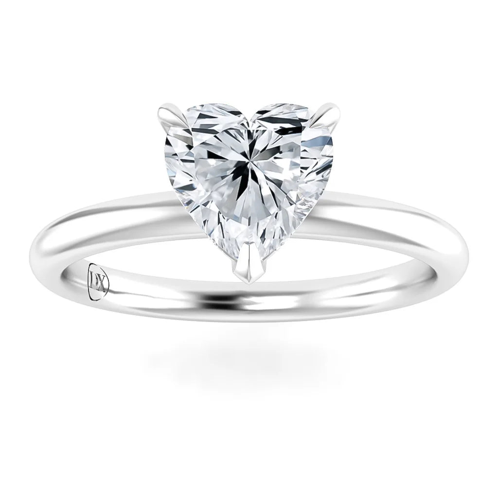 A silver ring with a heart-shaped clear diamond set on a simple, polished band.