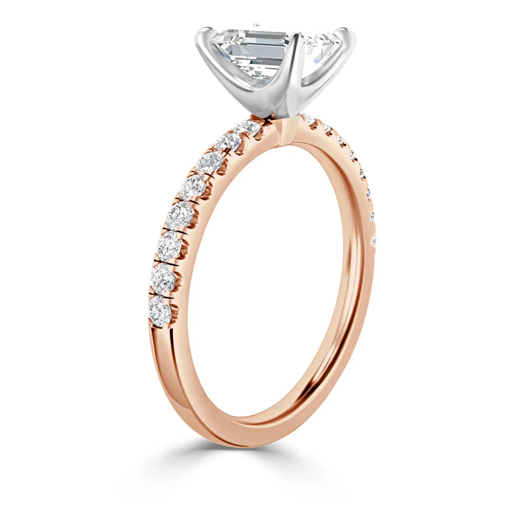 Rose gold ring with side diamonds and a large center diamond in a white gold prong setting, shown from an angle.