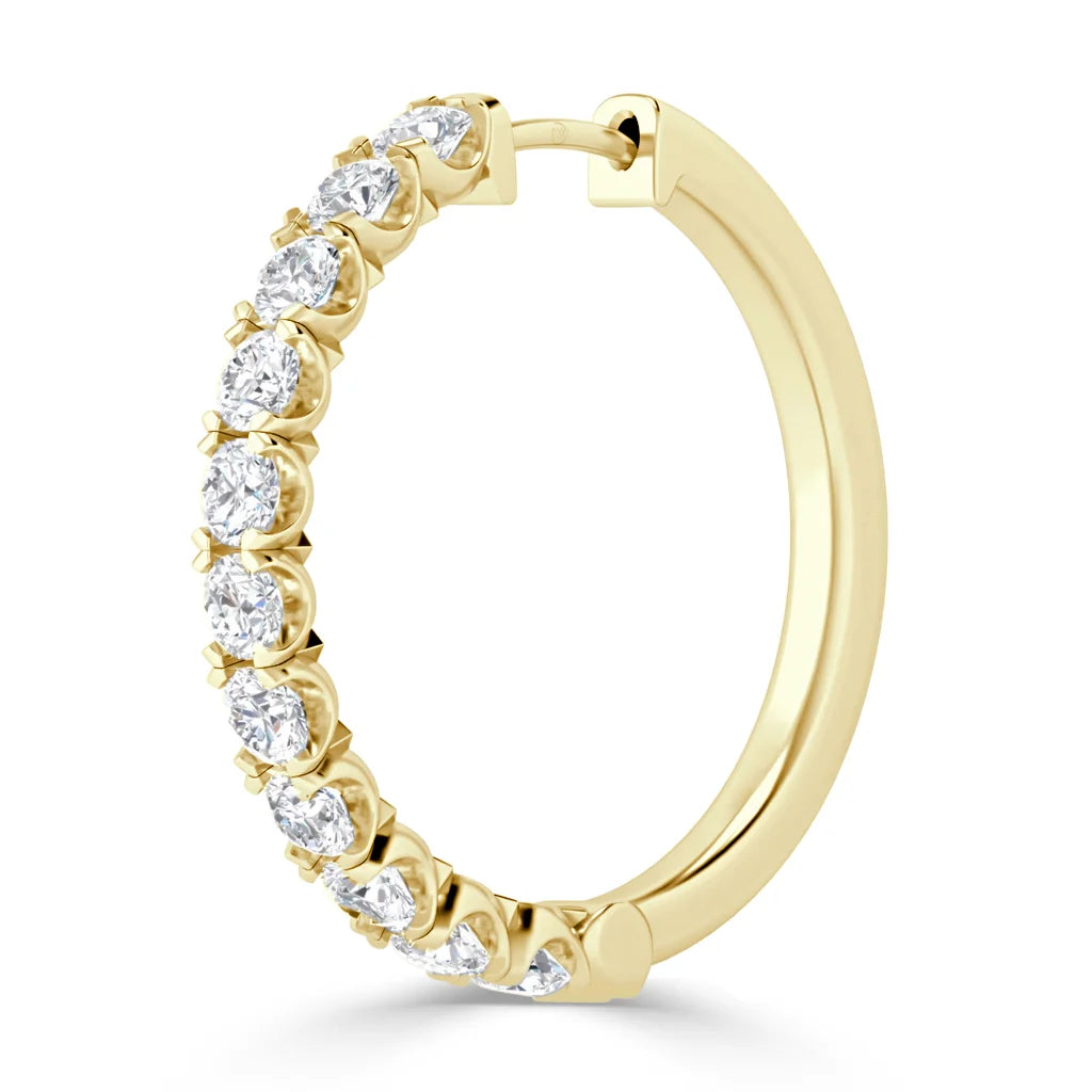 A gold hoop earring set with round, sparkling white diamonds along the front outer edge.