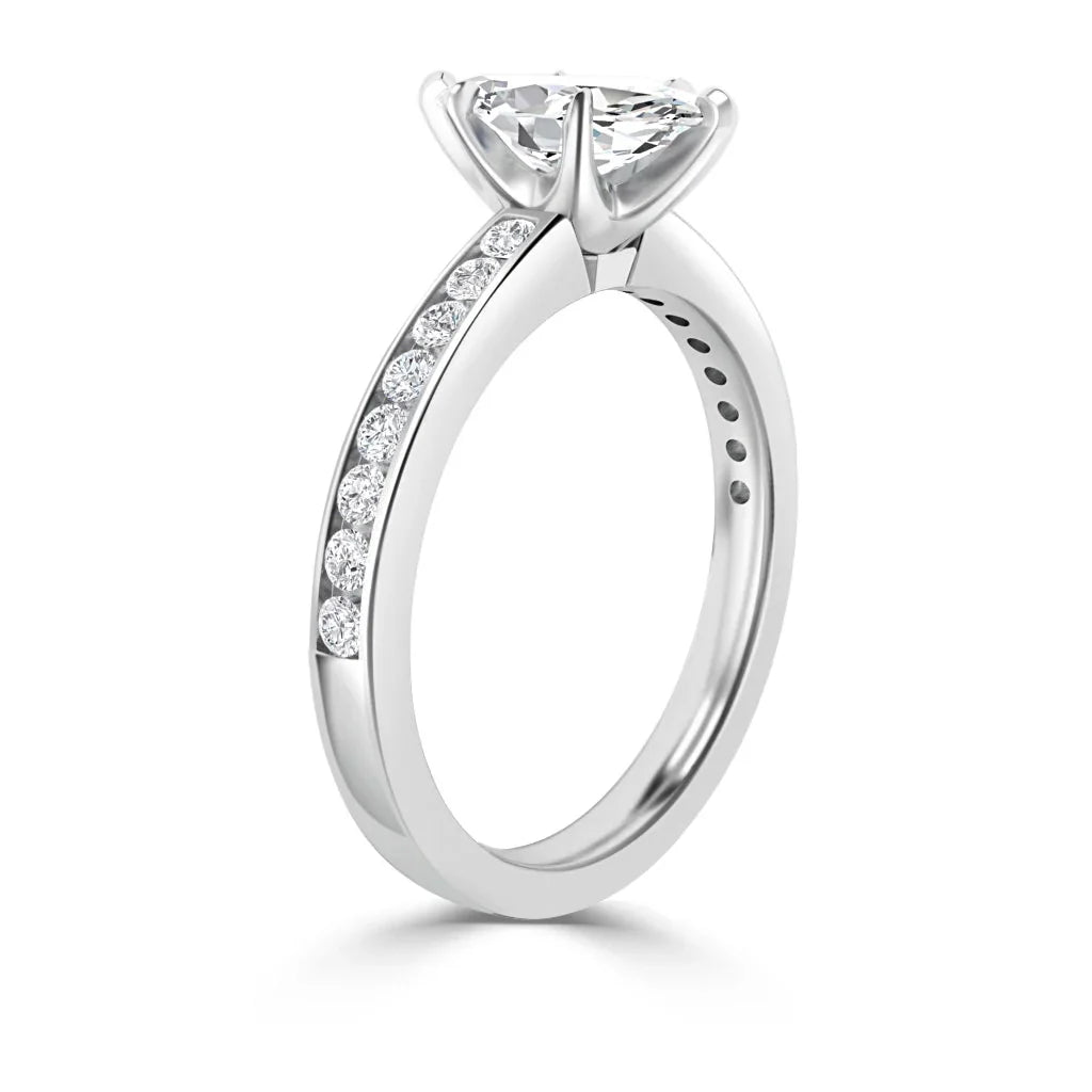 A white gold ring with a large round diamond and small diamonds set along the band’s top half.