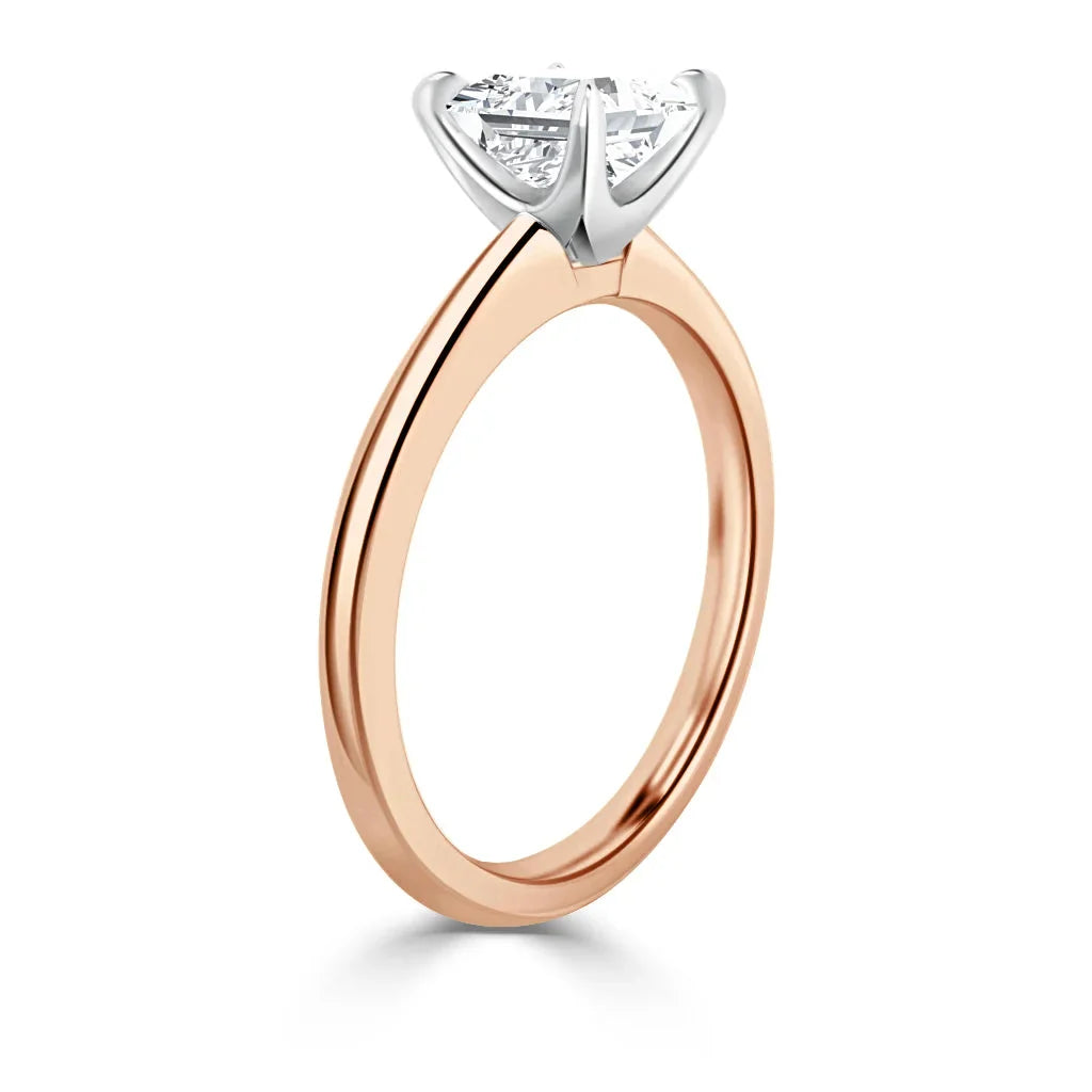 A rose gold solitaire ring with a prong-set round diamond and a white gold claw setting, shown in profile.
