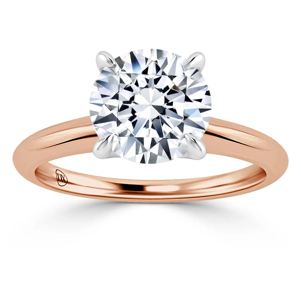 A rose gold ring with a large round diamond solitaire in a four-prong white gold setting.