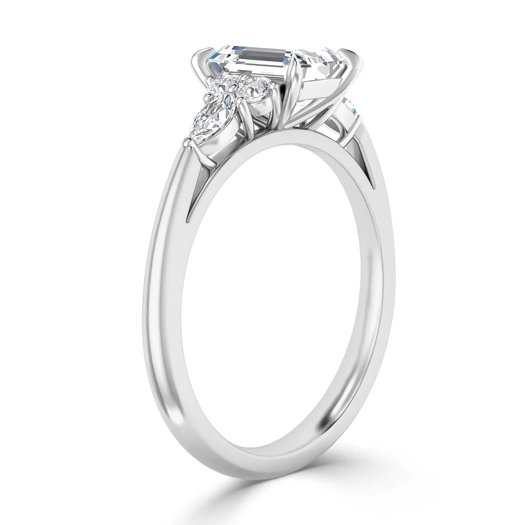 A silver ring with a large emerald-cut diamond and small side stones on a sleek, polished band.