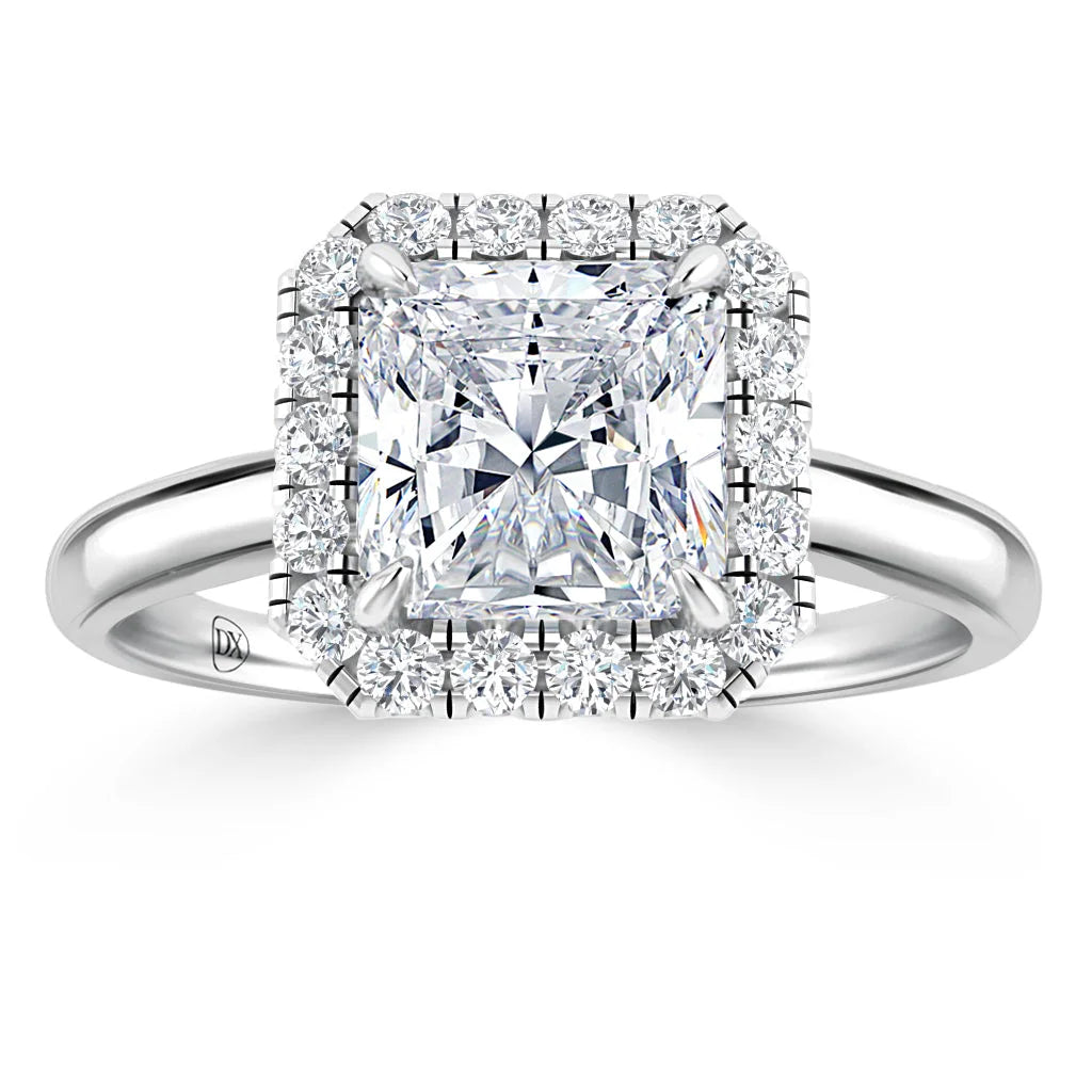 A square-cut diamond ring with a halo of smaller diamonds set on a polished silver band.