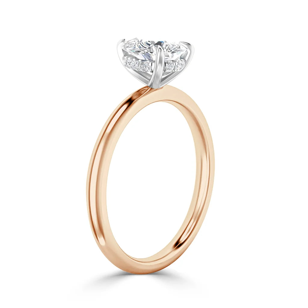 A rose gold ring with a round diamond solitaire set in a white gold prong setting, side view, on white background.
