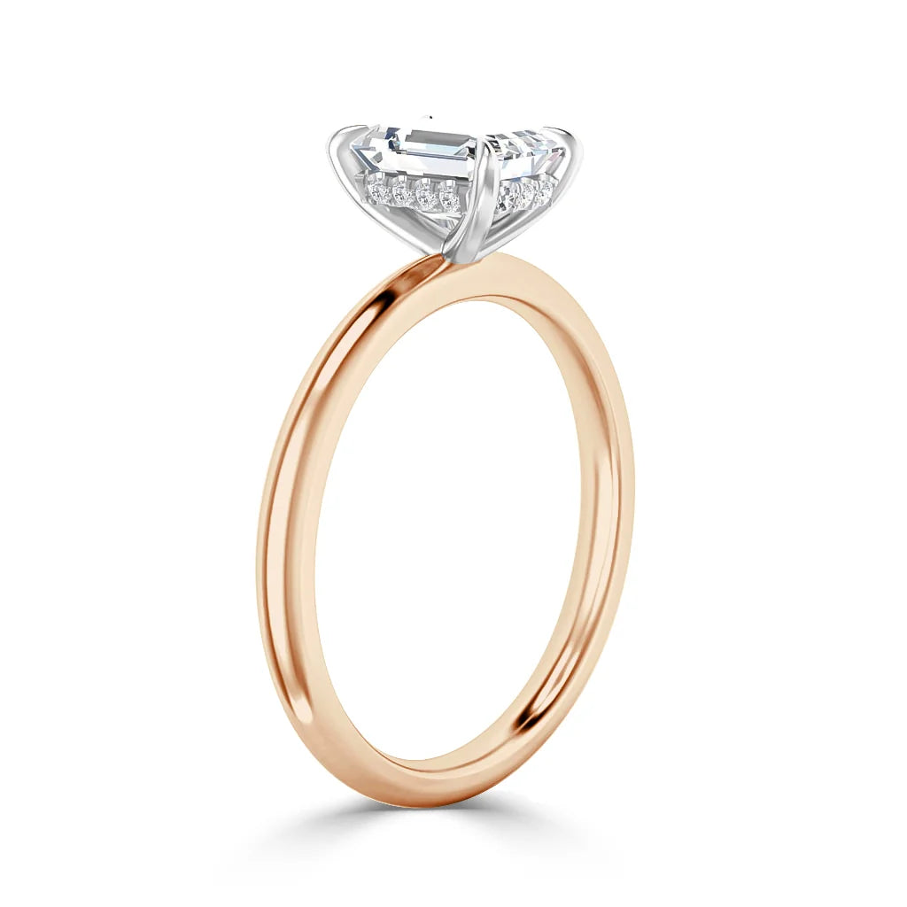 A rose gold ring with a large emerald-cut diamond and small accent diamonds under the setting.
