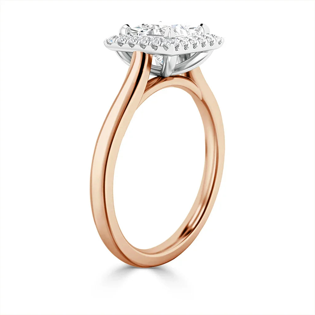 A rose gold ring with a round diamond halo setting, featuring a slim, elegant band against a white background.