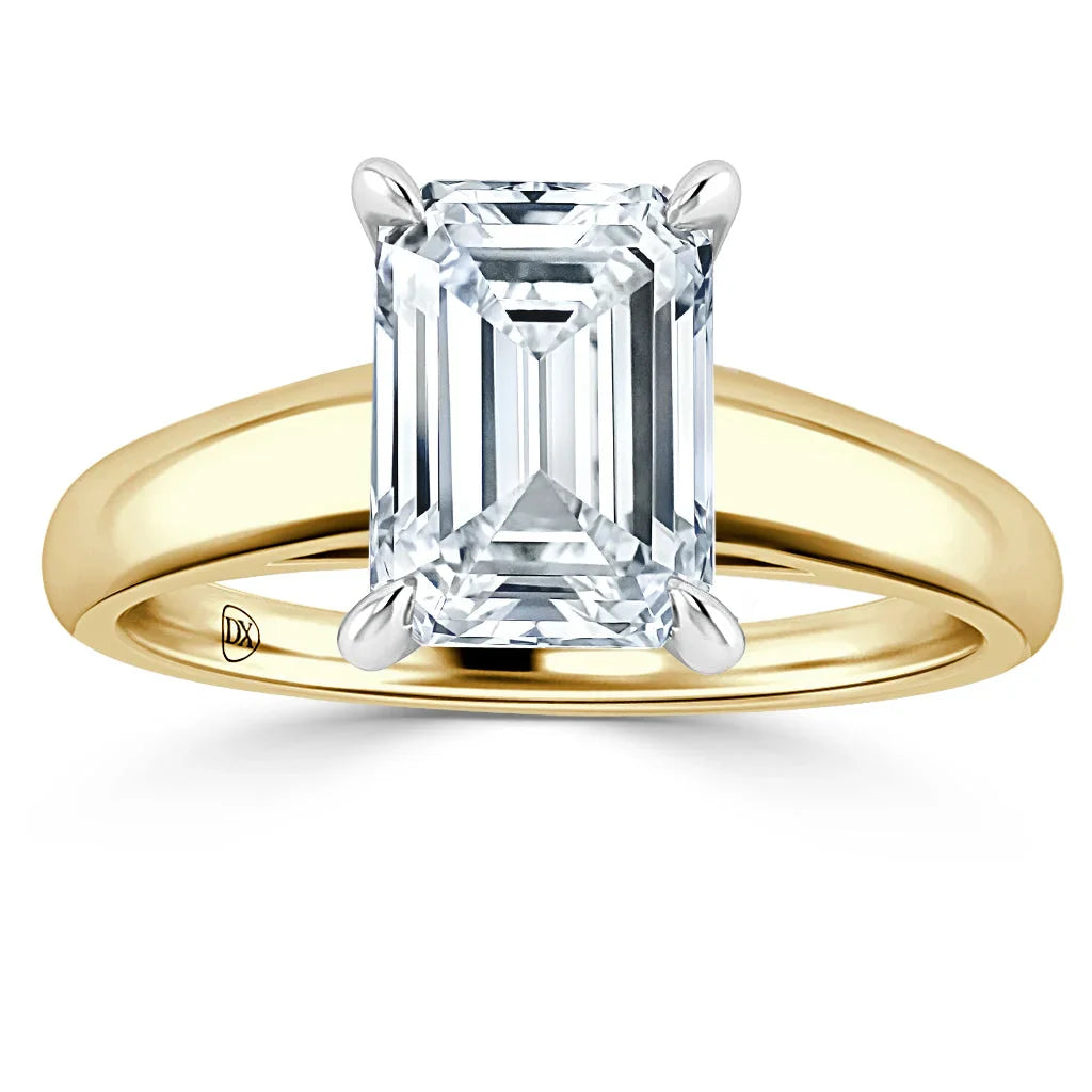 A gold band ring with a large emerald-cut diamond set in four prongs, shown on a white background.