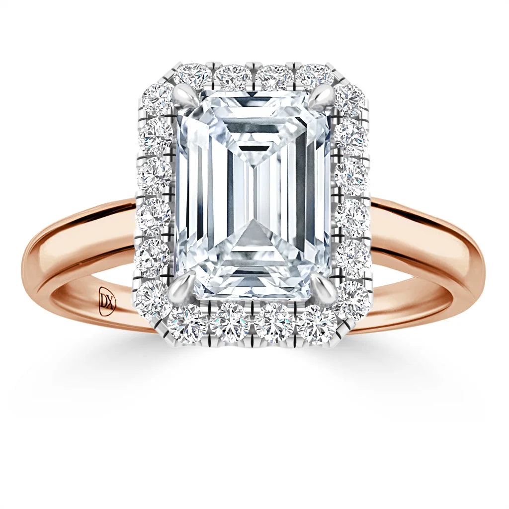 Emerald-cut diamond ring with a halo of small diamonds set on a rose gold band, displayed on white background.