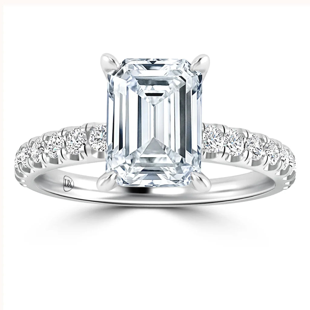 Emerald-cut diamond ring with a pavé diamond band set in white metal, viewed from the front.