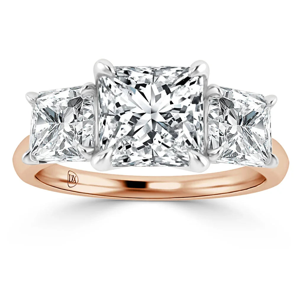 A rose gold ring with three princess-cut diamonds set in a row, center stone larger than the side stones.