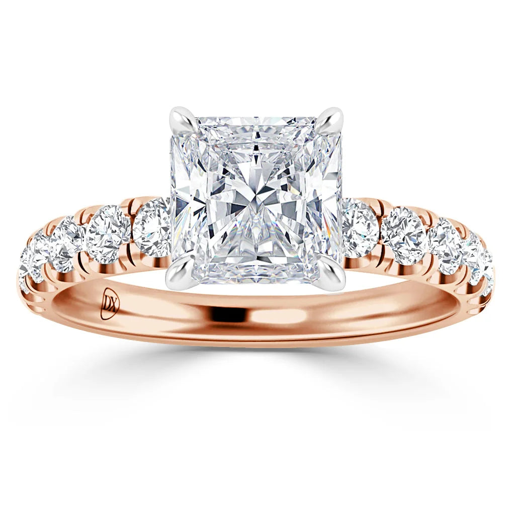A rose gold ring with a large princess-cut diamond and round diamonds set along the band.
