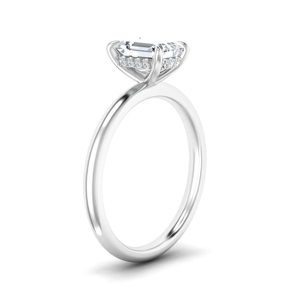 A silver solitaire ring with an emerald-cut diamond and small accent stones on the setting, shown on a white background.