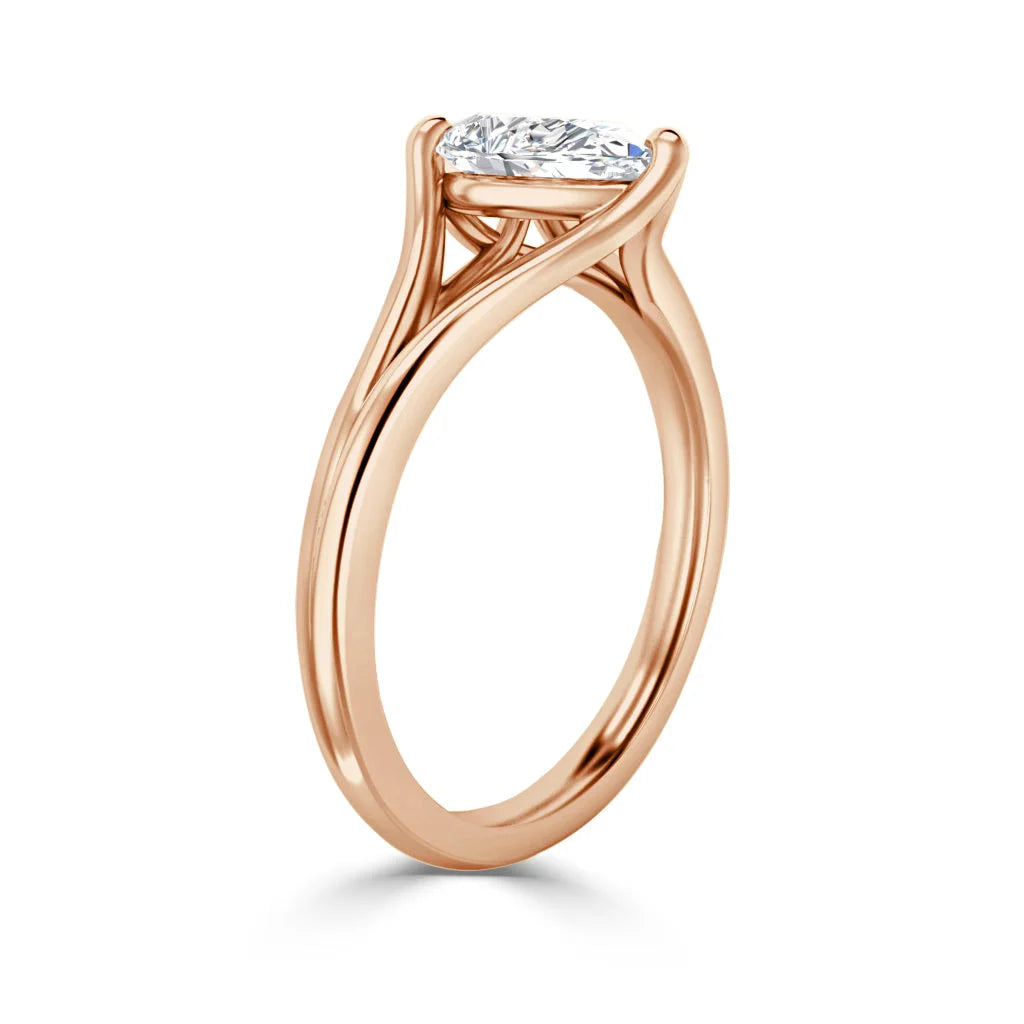 Rose gold ring with a raised, oval-cut diamond solitaire in a four-prong setting against a white background.