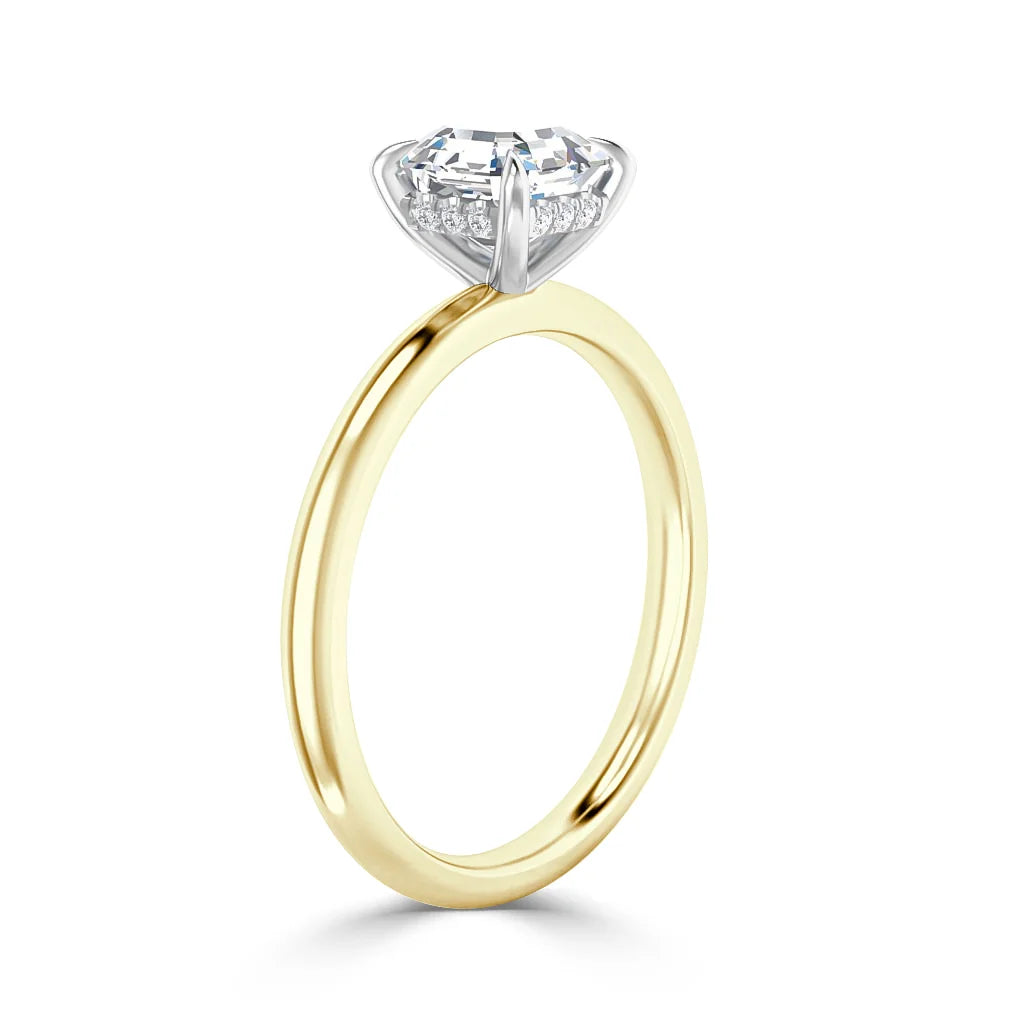 A gold ring with a round, prong-set diamond in a white gold setting, shown on a white background.