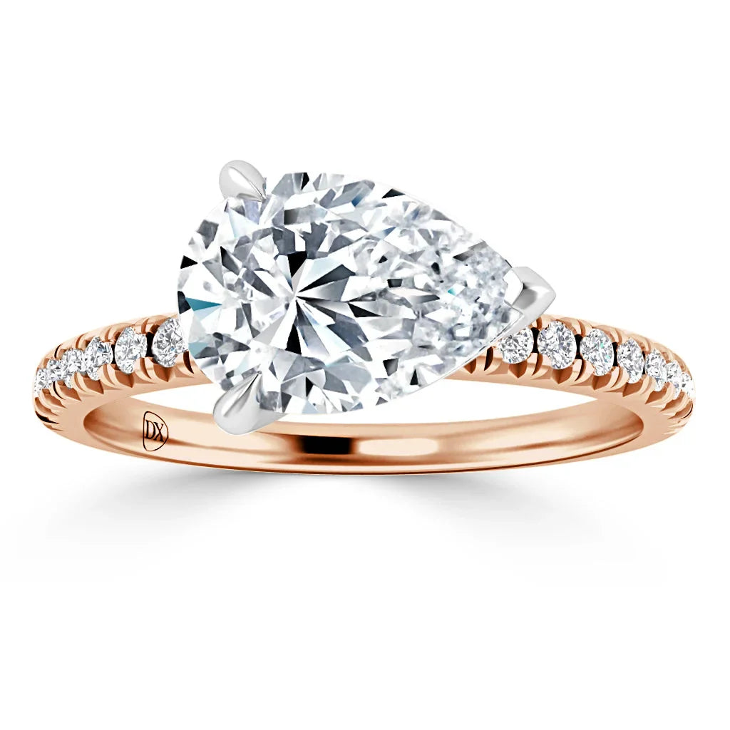 Rose gold ring with a large pear-shaped diamond and small diamonds on the band, on a white background.