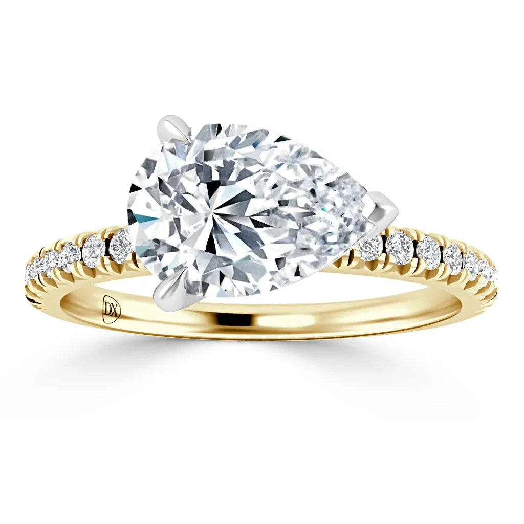 Gold ring with a large pear-shaped diamond and small diamonds on the band, set against a white background.