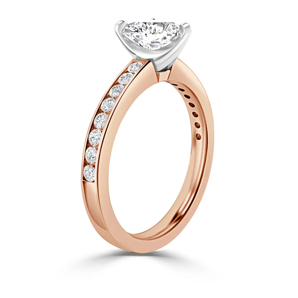A rose gold ring with side diamonds on the band and a large round solitaire diamond in a prong setting.